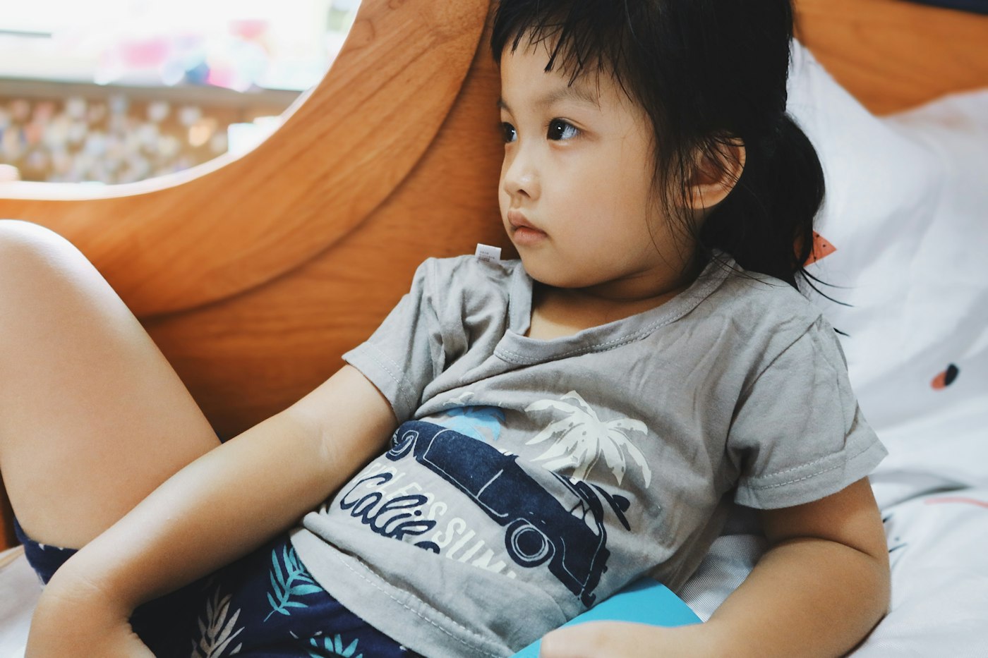 A young child resting on a bed while feeling unwell