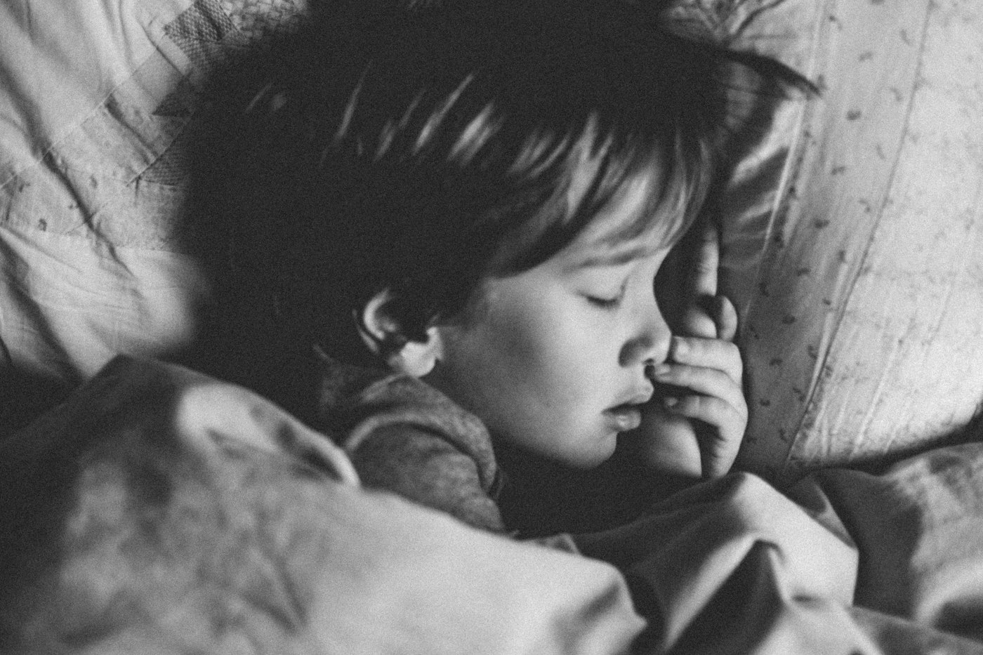 A young child sleeping under a blanket while resting at home with a fever