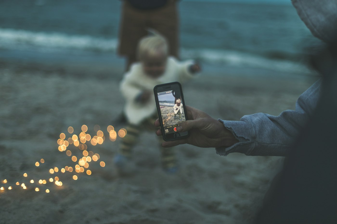 A parent holding up a smartphone to take a photo of a toddler